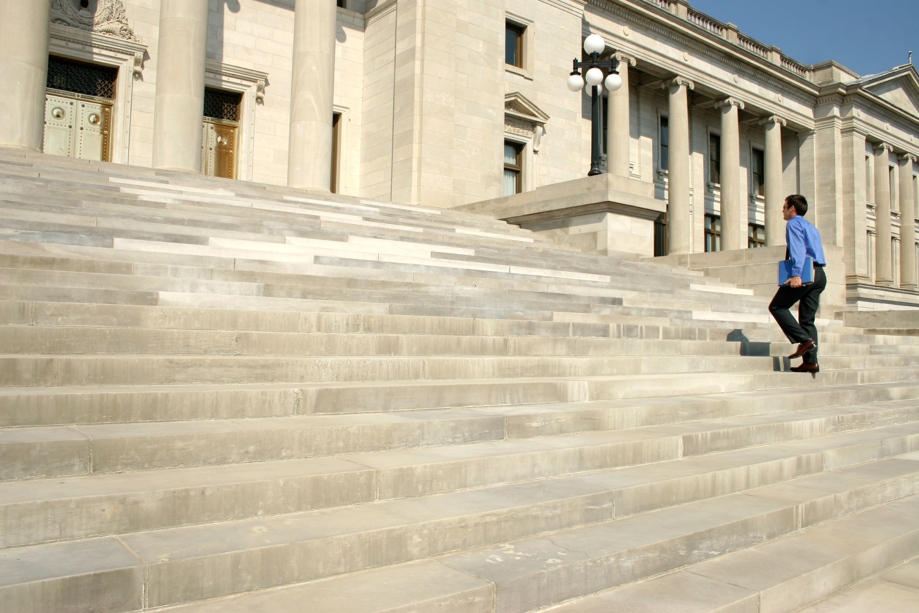 Man walking up the outside stairs of a government building.