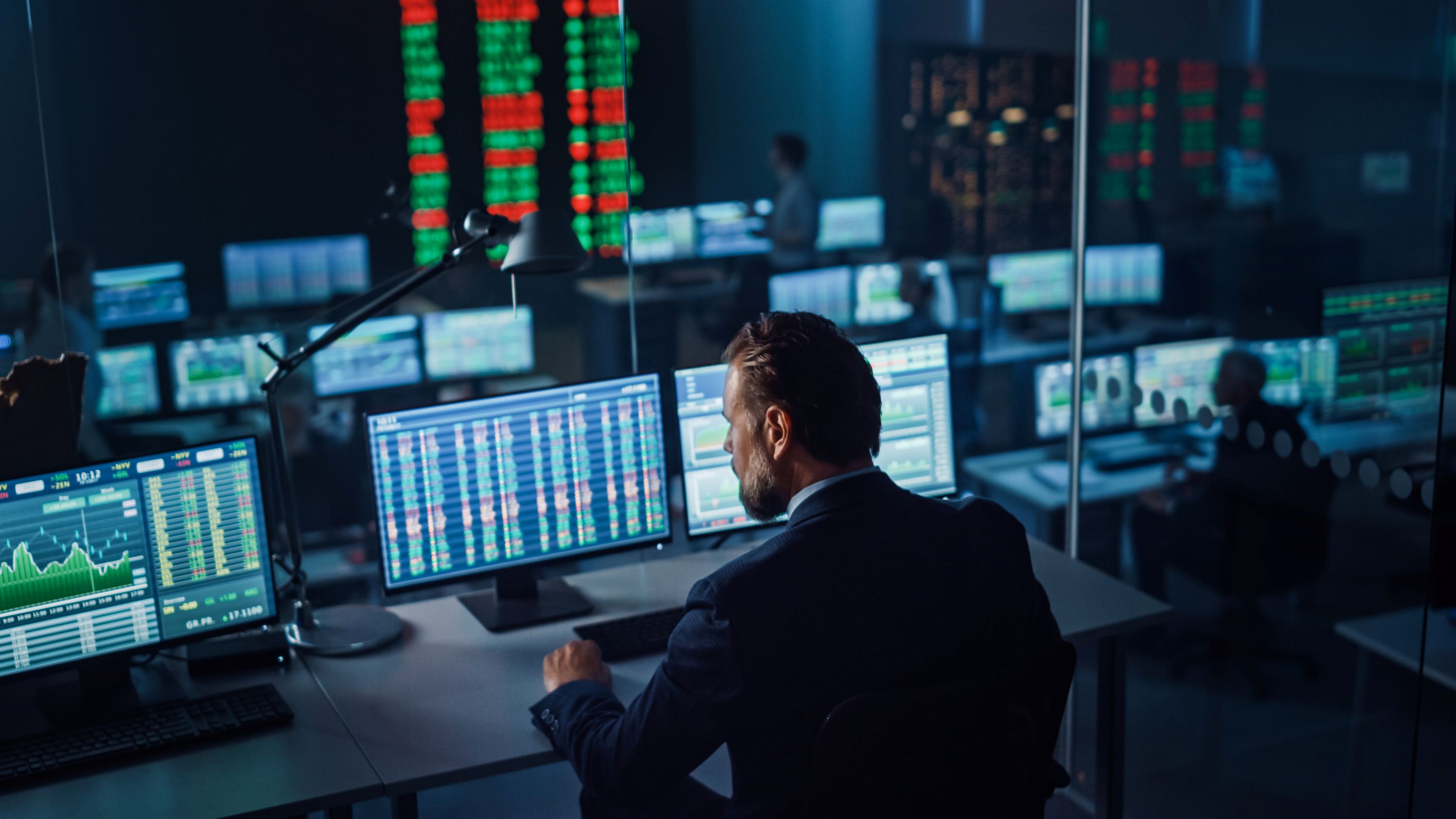 Financial services worker at a desk with multiple computer monitors.