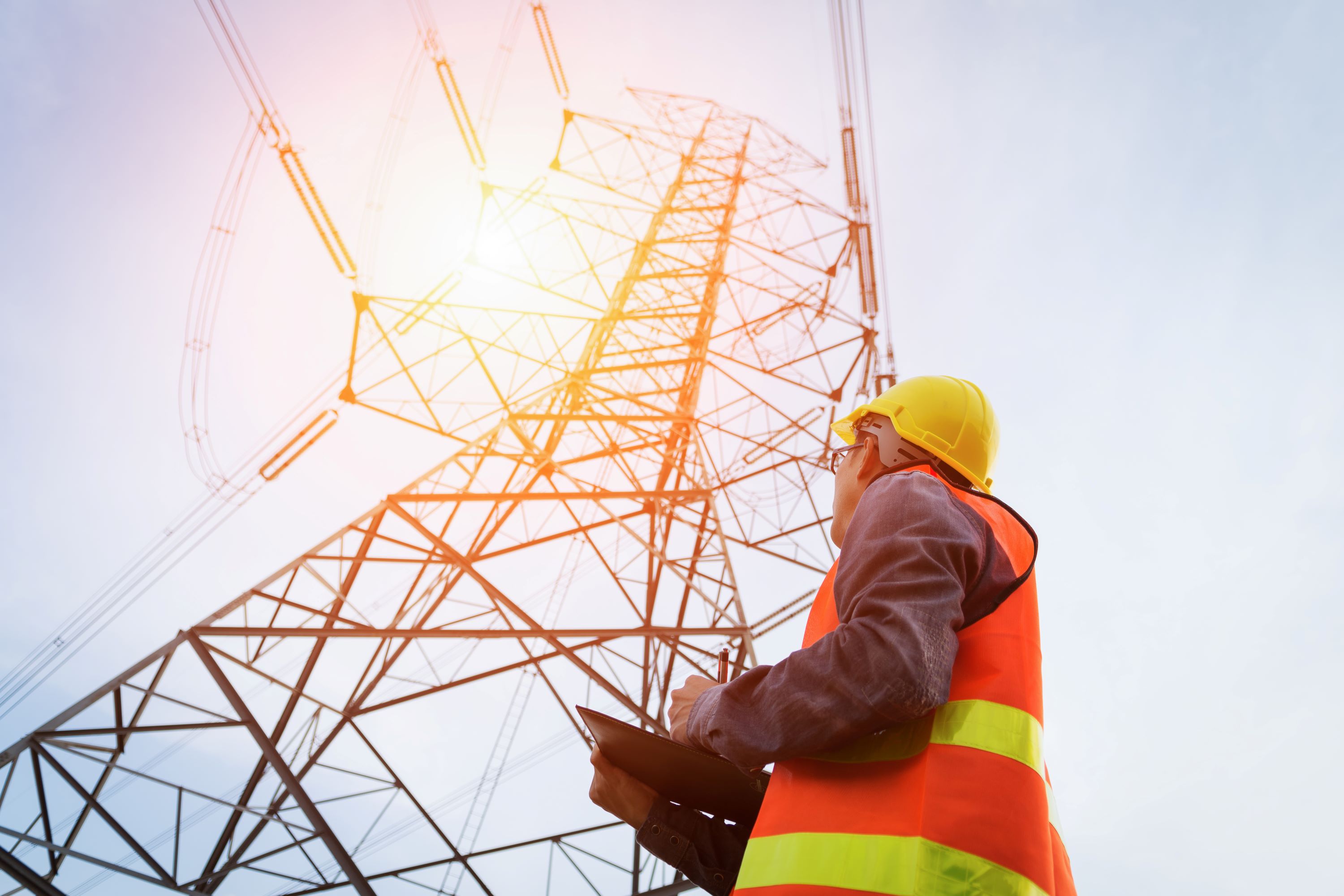 Energy worker looking up at a powerline structure.