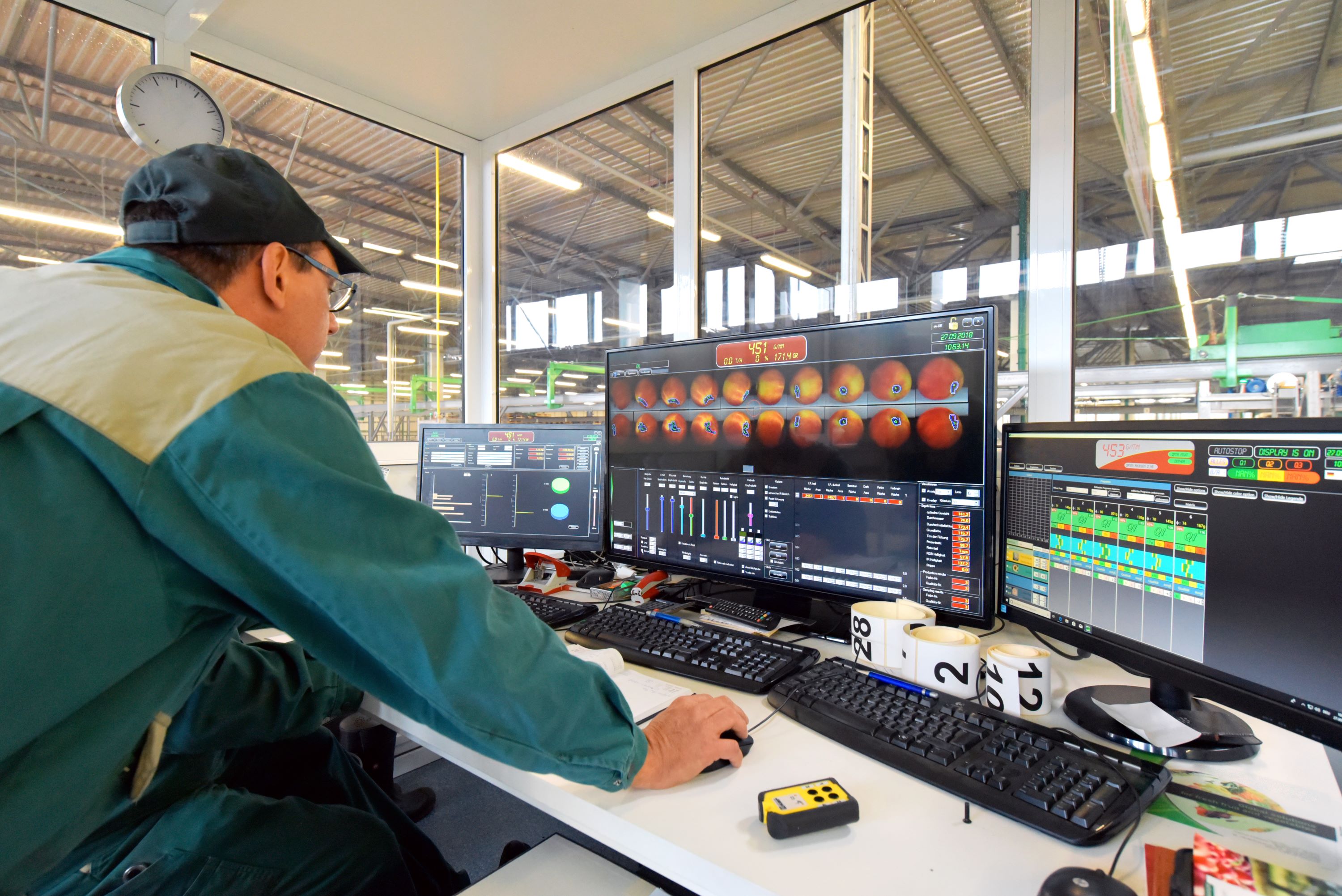 Agriculture worker at a computer in a crop processing facility.