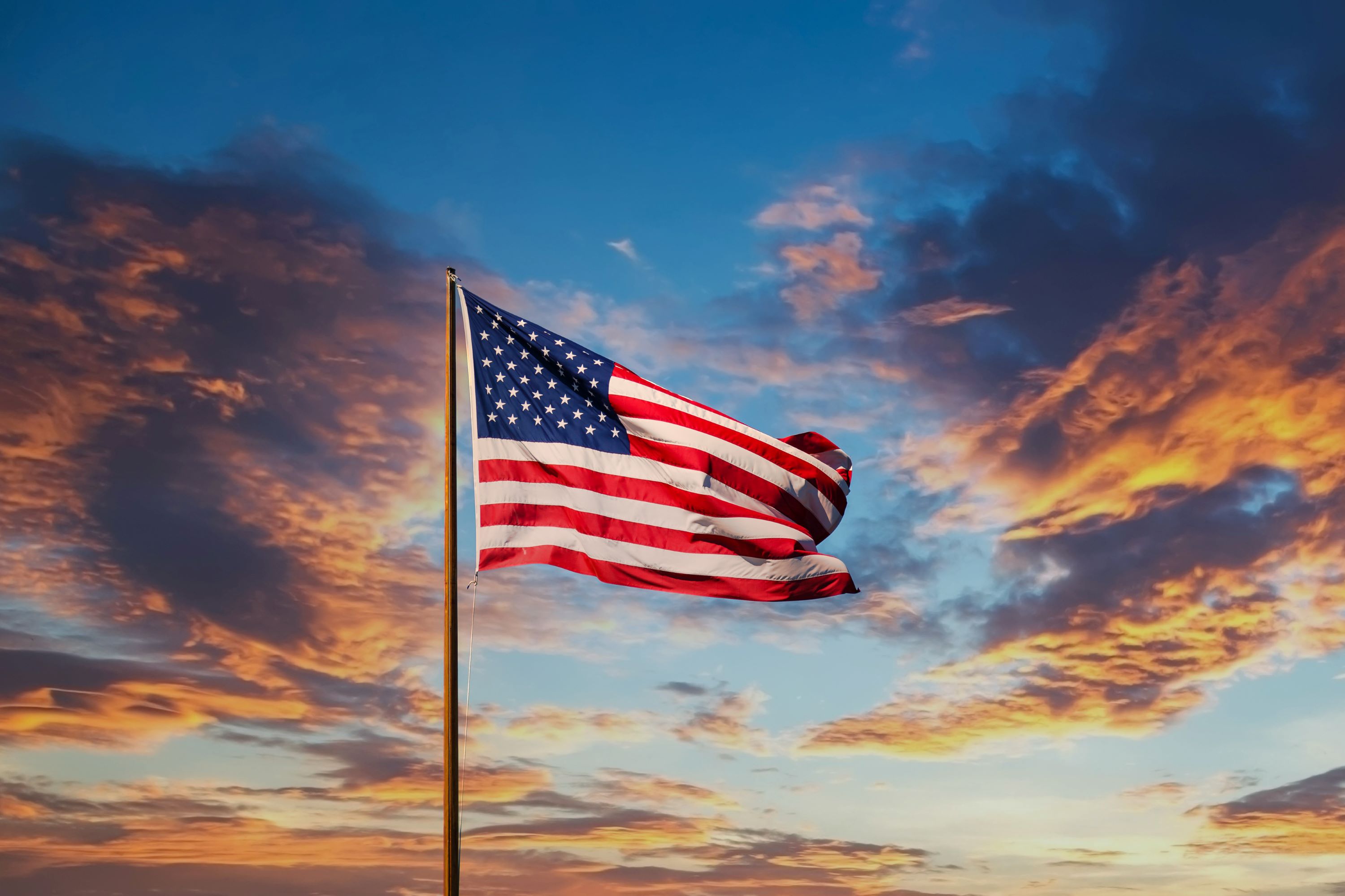 United States flag at full mast against sunset background