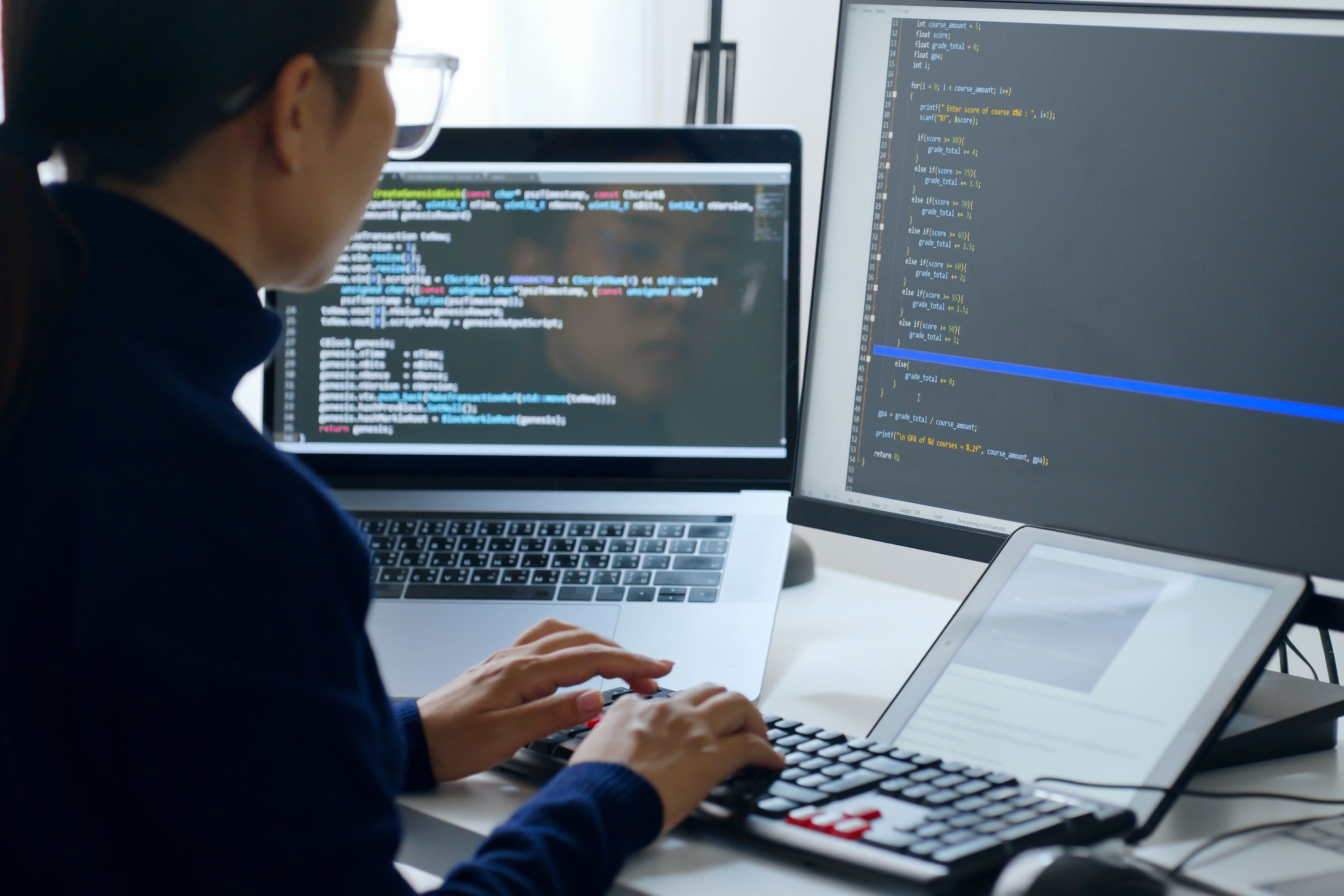 IT professional using a desktop computer, laptop, and pad device.