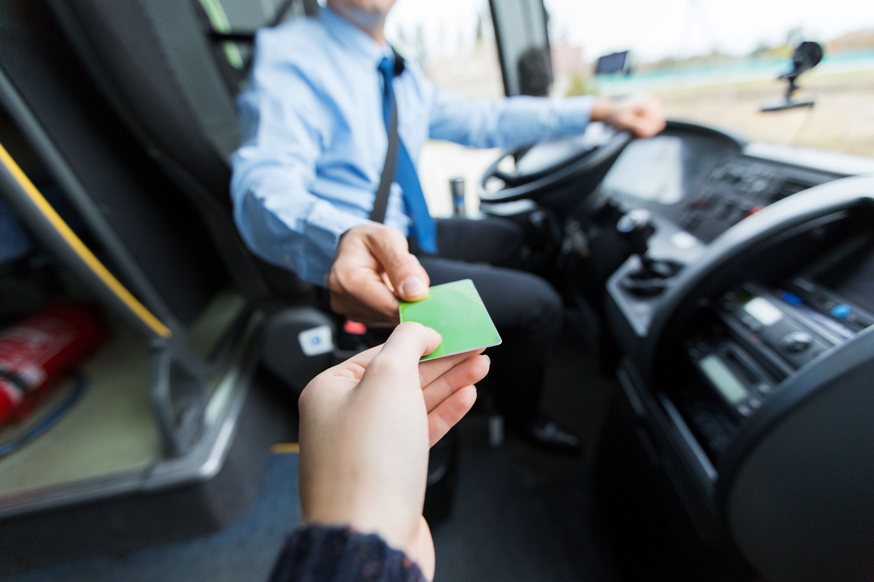 Commuter handing a bus driver a bus fare card.