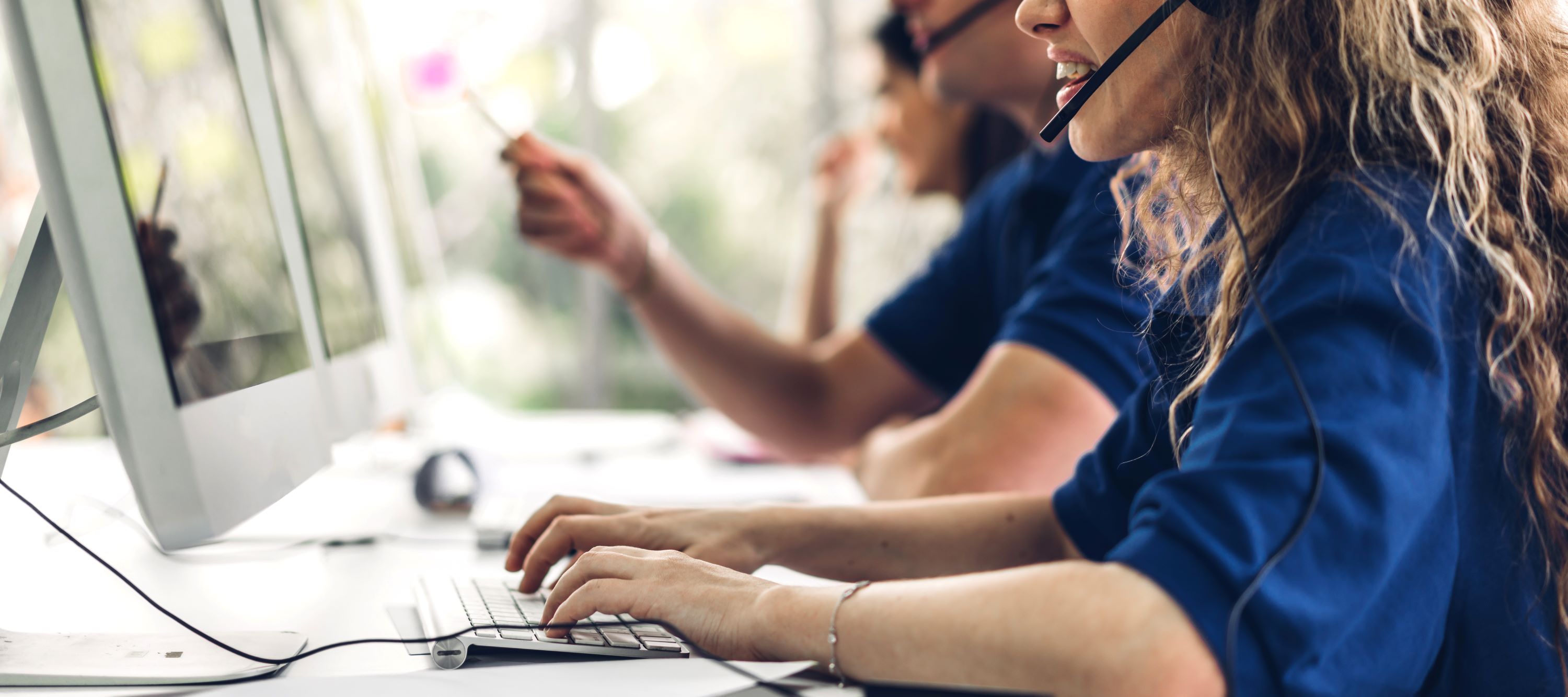 Customer service professionals using desktop computers and headsets.