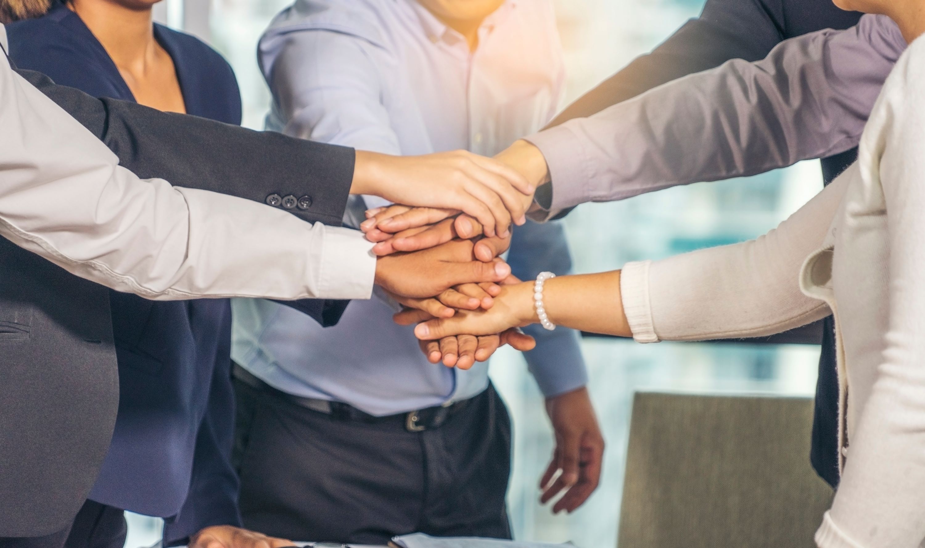 Seven professionals stacking their hands together.