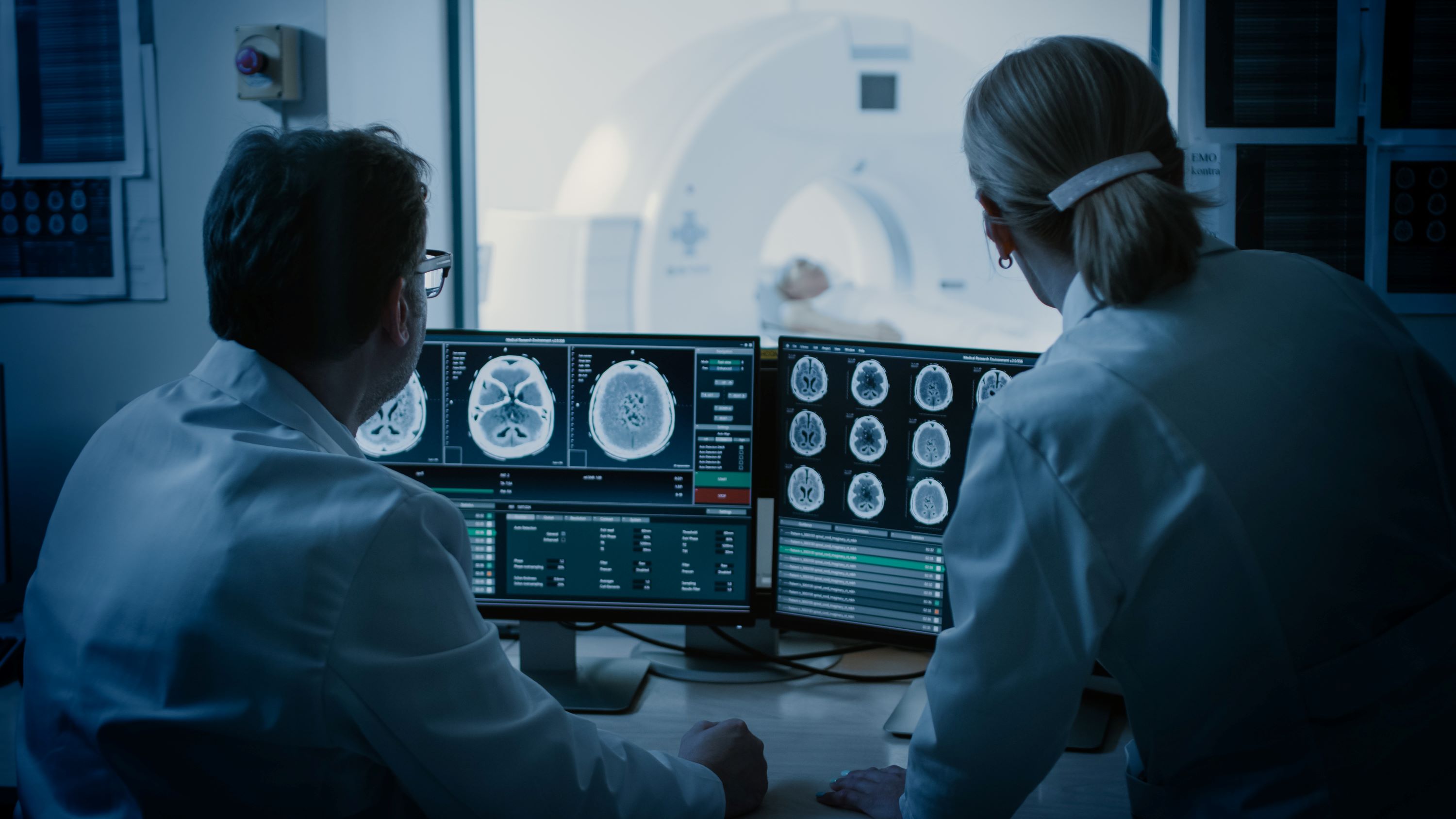 Two healthcare professionals monitoring a computer controlling an MRI machine